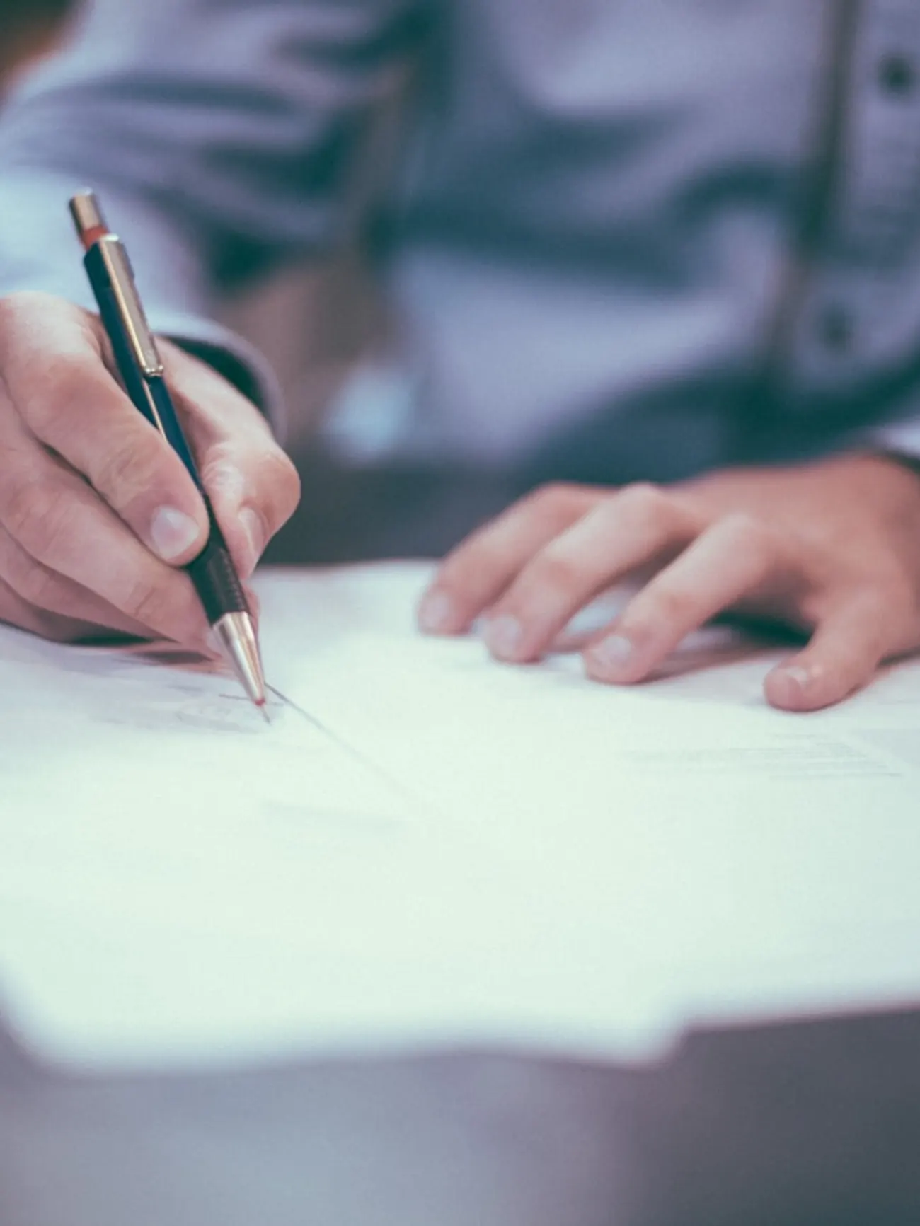 Mano tomando notas con un bolígrafo sobre un documento en la mesa de un despacho