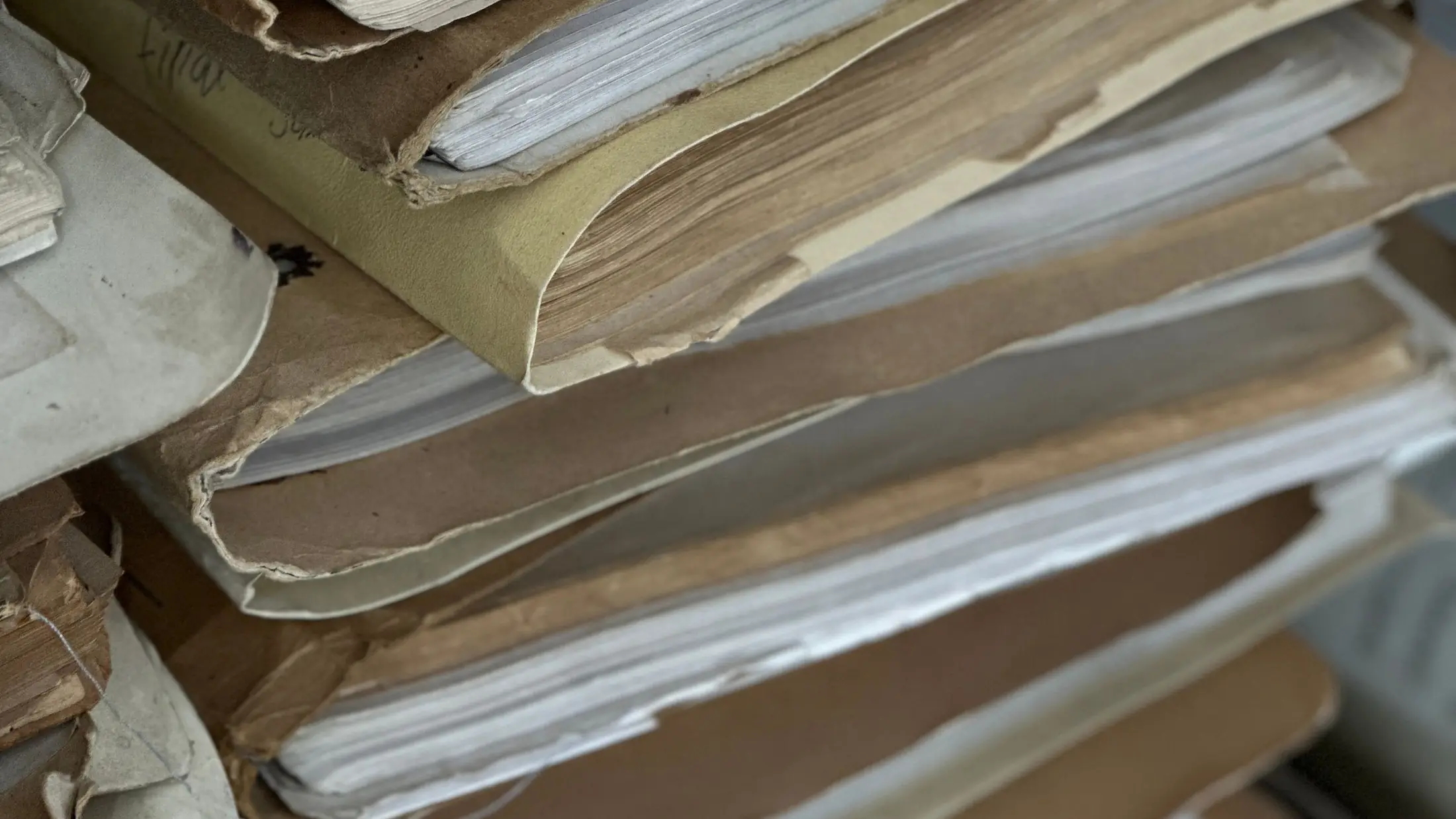 Expedientes de papel apilados en carpetas de cartulina dentro de un archivo